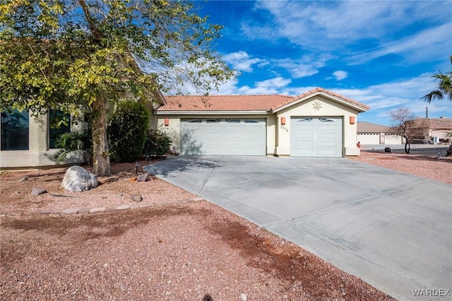 view of front of house featuring a garage, a tiled roof, concrete driveway, and stucco siding