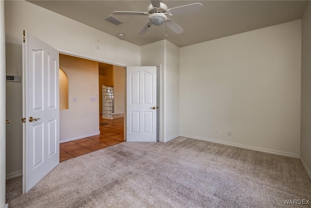 unfurnished bedroom featuring light carpet, light tile patterned floors, baseboards, visible vents, and a ceiling fan