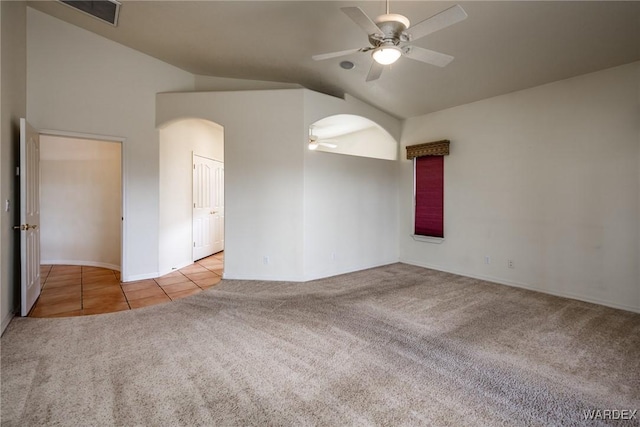 spare room featuring light tile patterned floors, visible vents, a ceiling fan, light colored carpet, and vaulted ceiling