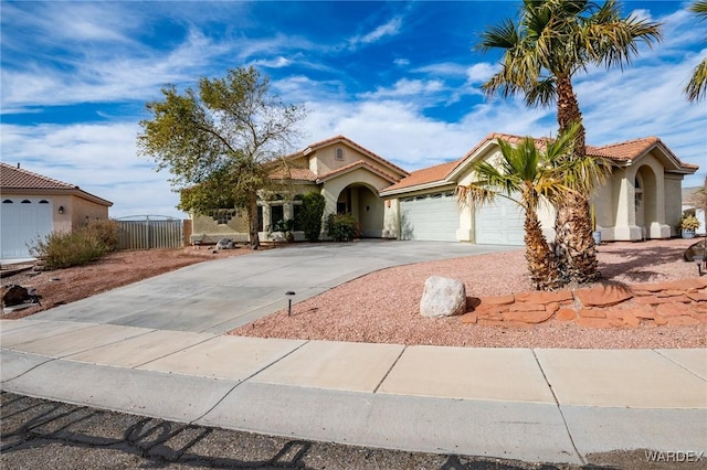 mediterranean / spanish home with a tile roof, driveway, an attached garage, and stucco siding