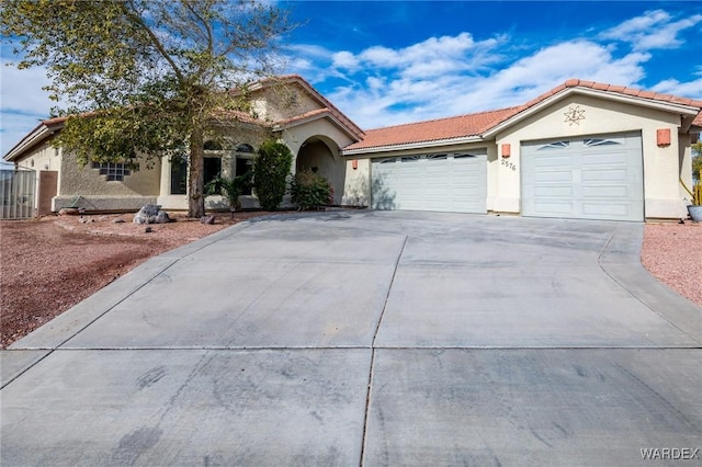 view of front of home featuring a garage, concrete driveway, a tile roof, and stucco siding