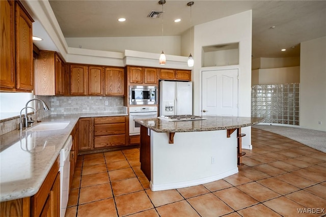 kitchen featuring a kitchen island, appliances with stainless steel finishes, a breakfast bar, brown cabinets, and a sink