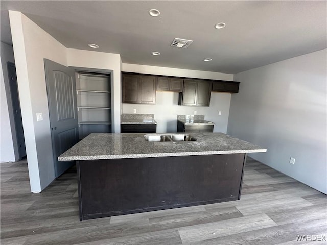 kitchen featuring visible vents, dark brown cabinetry, wood finished floors, and a center island