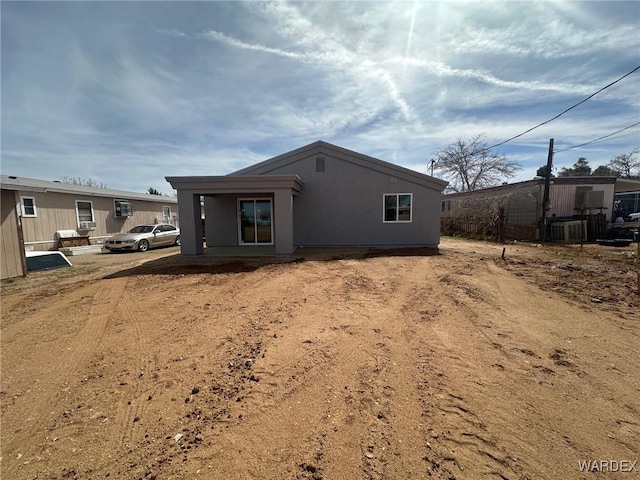 rear view of house featuring stucco siding