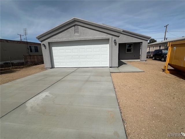 view of front of home with stucco siding, concrete driveway, and an attached garage