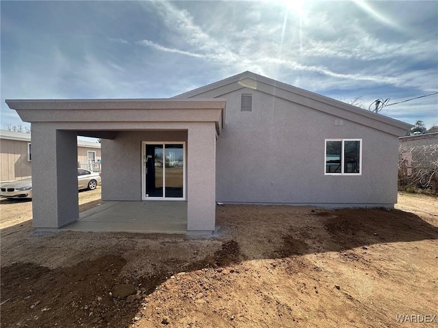 rear view of house featuring a patio area and stucco siding