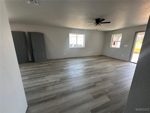 unfurnished room with wood finished floors, visible vents, and ceiling fan