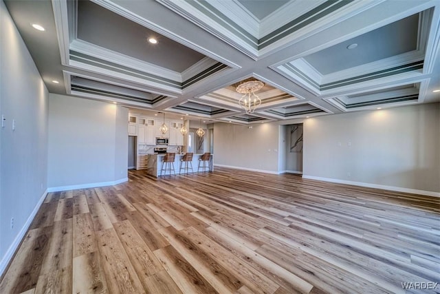 unfurnished living room featuring a chandelier, baseboards, crown molding, and light wood finished floors