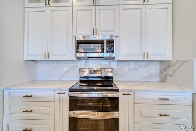 kitchen with stainless steel appliances, light stone counters, and white cabinetry