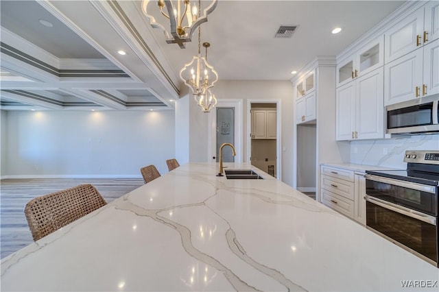 kitchen with glass insert cabinets, an inviting chandelier, appliances with stainless steel finishes, and a sink