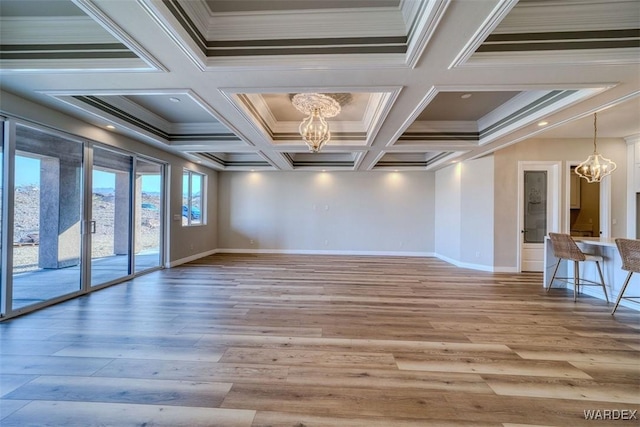 unfurnished room featuring a chandelier, ornamental molding, wood finished floors, and baseboards