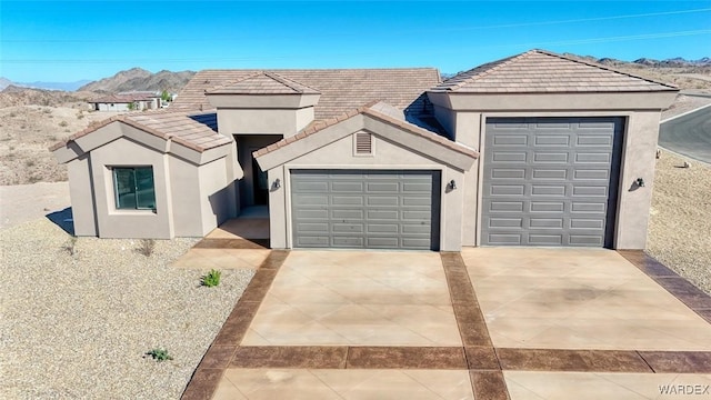 view of front of property with a garage, a tiled roof, a mountain view, and stucco siding