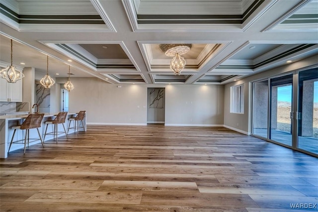 interior space with baseboards, light wood-style floors, ornamental molding, and a notable chandelier