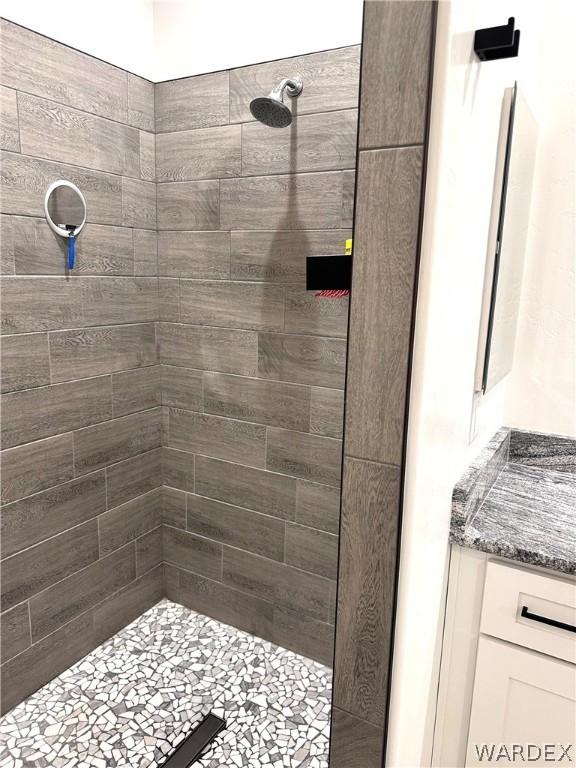 bathroom featuring tiled shower and vanity