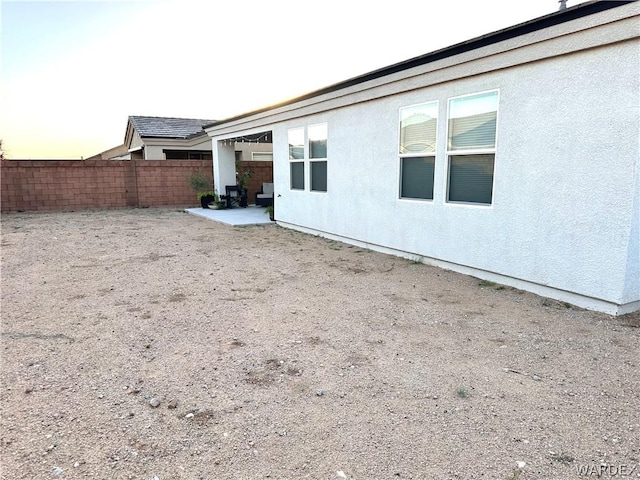 back of property featuring stucco siding, fence, and a patio