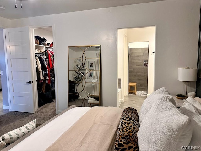 bedroom featuring a closet, light carpet, connected bathroom, and a spacious closet