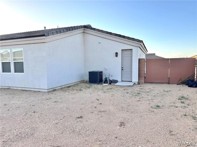 back of property featuring central air condition unit, a gate, fence, and stucco siding