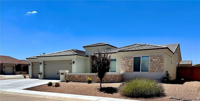 prairie-style home featuring a tile roof, stucco siding, concrete driveway, an attached garage, and stone siding