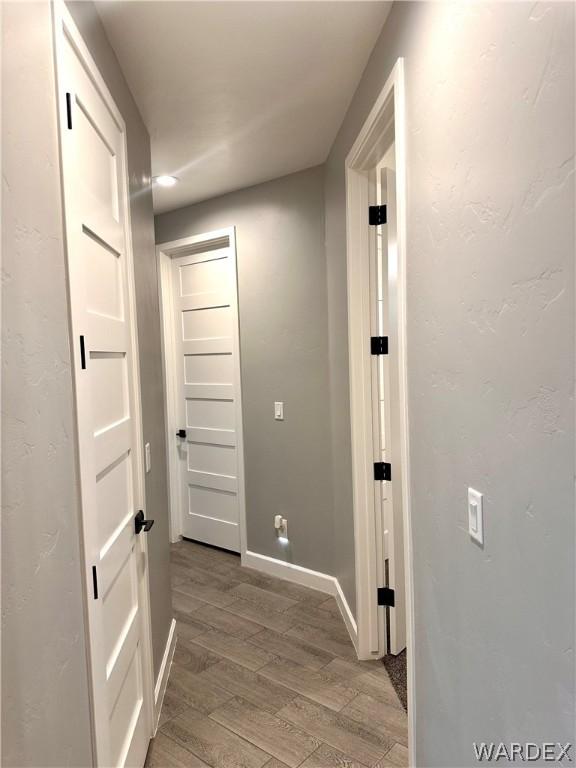 corridor featuring baseboards and light wood-style floors