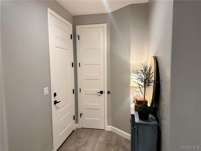 doorway featuring baseboards and wood finished floors