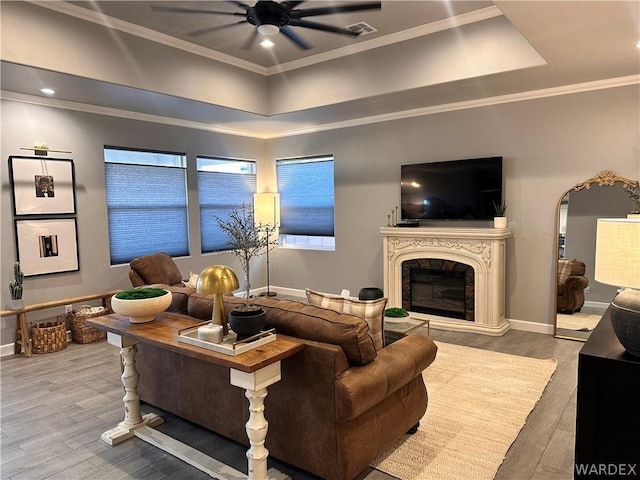 living room featuring ornamental molding, ceiling fan, a premium fireplace, and wood finished floors