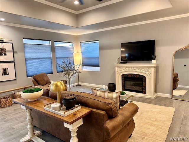 living room with ornamental molding, baseboards, a premium fireplace, and wood finished floors