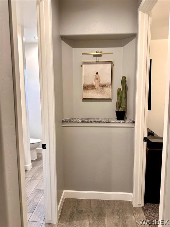 hall featuring light wood-style flooring and baseboards