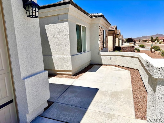 view of side of property featuring a patio, a mountain view, and stucco siding