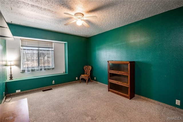 unfurnished room featuring ceiling fan, visible vents, carpet floors, and a textured ceiling