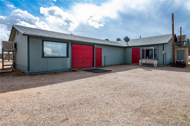 view of front of property with an attached garage, central AC, and dirt driveway