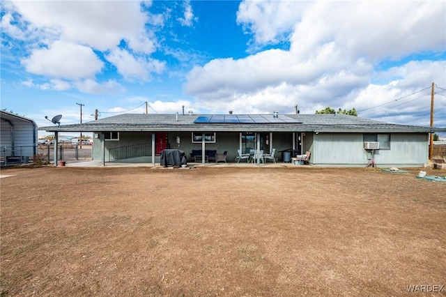 back of house featuring a patio area, solar panels, a carport, and fence