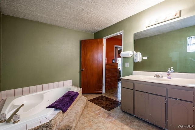 full bathroom featuring tile patterned floors, a garden tub, a textured ceiling, and vanity