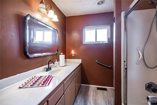 full bathroom with vanity, wood finished floors, visible vents, a shower, and a textured ceiling