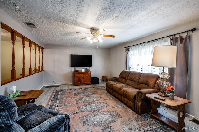 living area with visible vents, baseboards, wood finished floors, a textured ceiling, and a ceiling fan