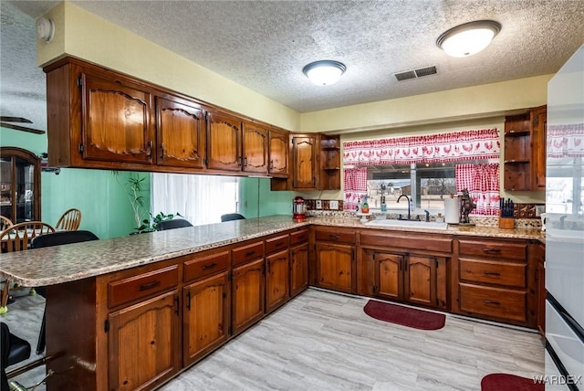 kitchen with visible vents, a sink, open shelves, a kitchen breakfast bar, and a peninsula