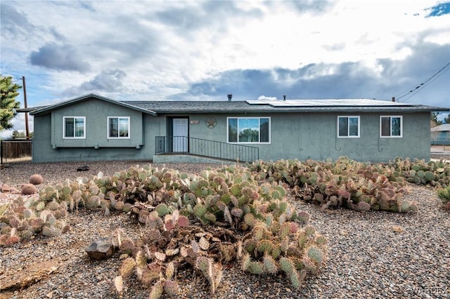 view of front of home featuring roof mounted solar panels and stucco siding