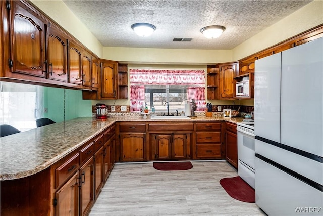 kitchen with visible vents, open shelves, a sink, a textured ceiling, and white appliances