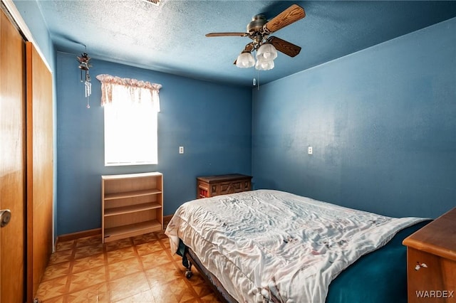 bedroom with a closet, baseboards, a textured ceiling, and ceiling fan