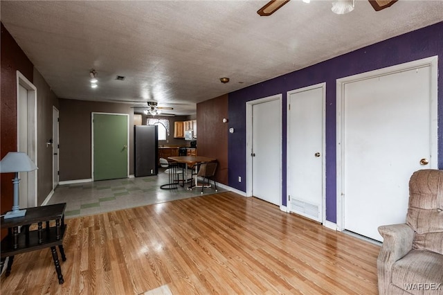 living area with visible vents, baseboards, ceiling fan, and light wood finished floors