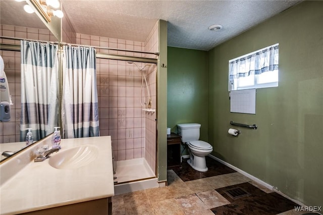 bathroom featuring a shower stall, baseboards, toilet, vanity, and a textured ceiling