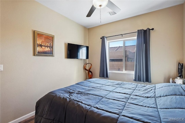 bedroom with ceiling fan, visible vents, baseboards, and wood finished floors