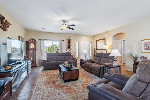 living room featuring baseboards, visible vents, a ceiling fan, and dark wood-type flooring