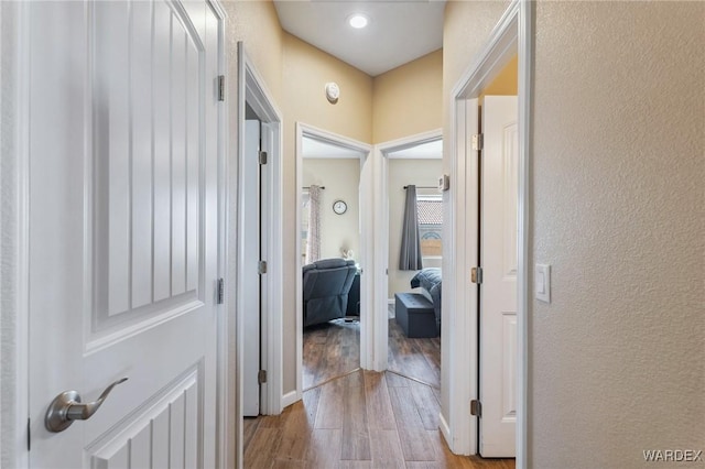 corridor with light wood-style floors and a textured wall