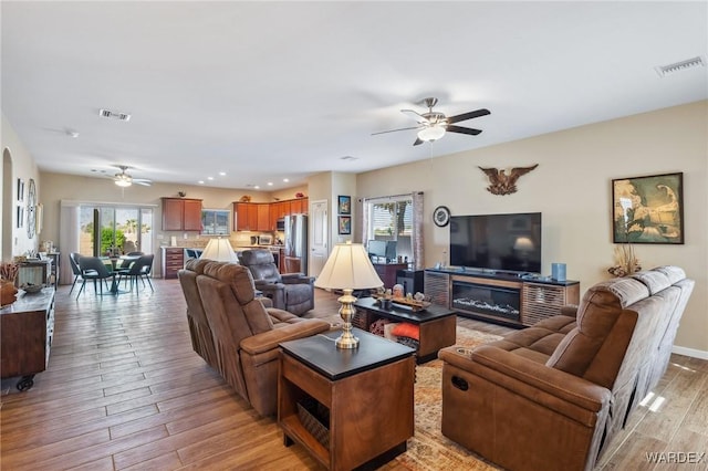 living area featuring light wood finished floors, visible vents, and a ceiling fan