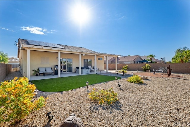 back of house with roof mounted solar panels, a fenced backyard, a patio, and stucco siding