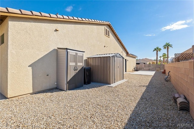 exterior space featuring a storage shed, a patio, a fenced backyard, and stucco siding