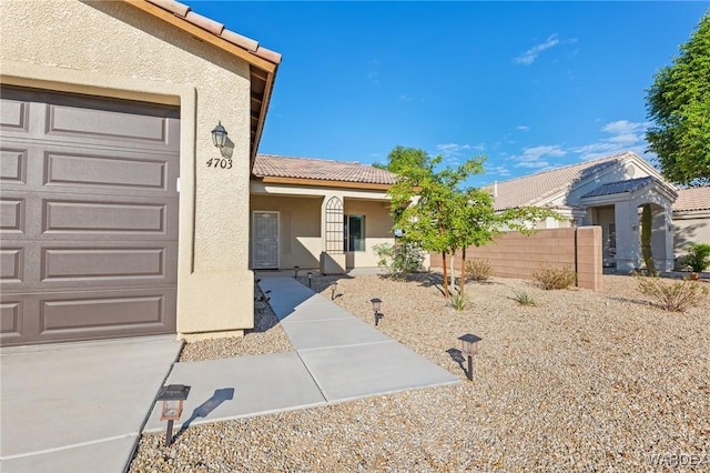 property entrance featuring a garage, a tiled roof, and stucco siding