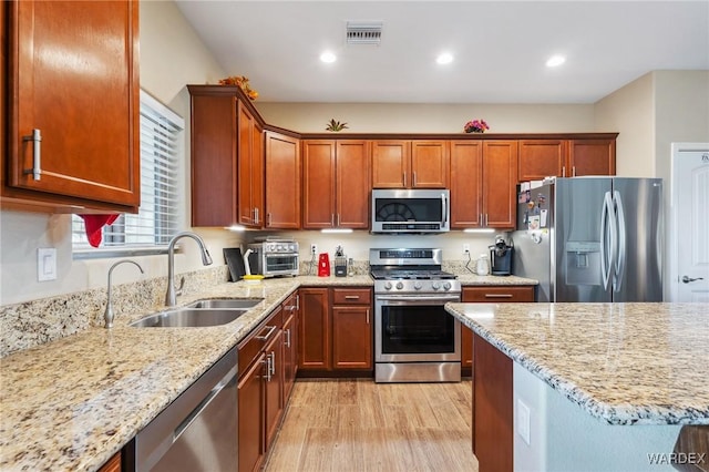 kitchen featuring stainless steel appliances, visible vents, a sink, and light stone counters