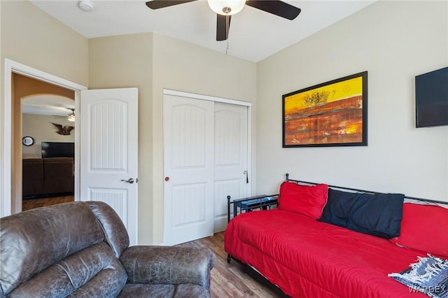 bedroom with arched walkways, a closet, ceiling fan, and wood finished floors