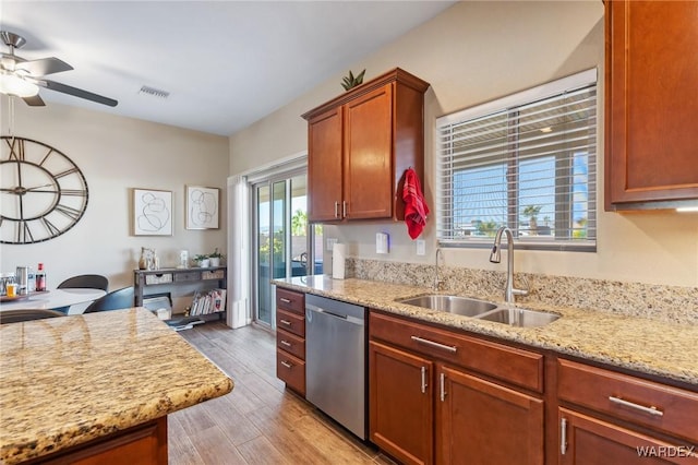 kitchen with light wood finished floors, visible vents, light stone countertops, stainless steel dishwasher, and a sink